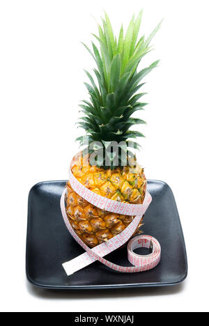 Reife lebendige Ananas auf einer schwarzen Platte mit Klebeband meter Stockfoto