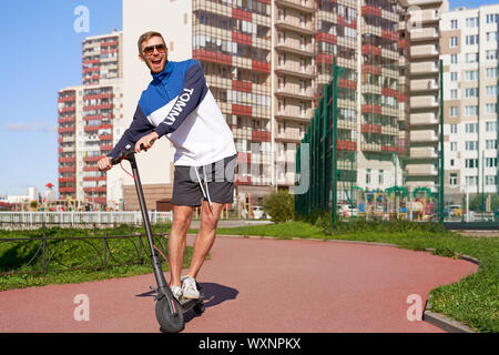 Frohen trendigen athletischer Kerl Antriebe eco Roller. Stockfoto