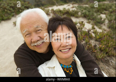Älteres Paar am Strand sitzen Stockfoto