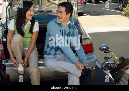 Paar, sitzen auf Heckschürze Autotyp Golfschuhe anziehen Stockfoto