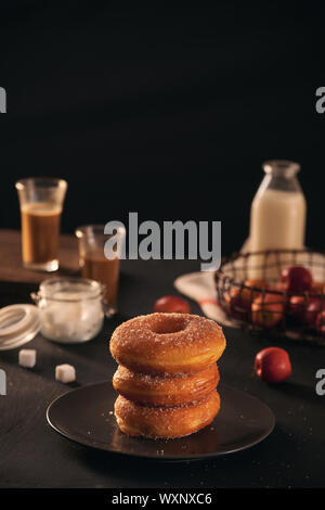 Frische Donuts mit Zucker Pulver und Kaffee mit Milch auf einen hölzernen Tisch. Frühstück im Dorf. Stockfoto