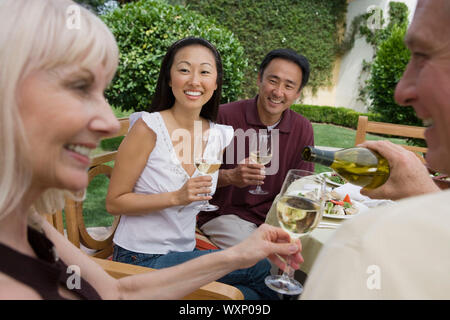 Zwei Paare trinken Wein im Garten Stockfoto