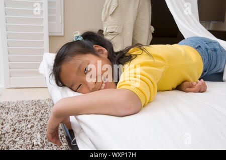 Mädchen auf dem Bett liegend und lächelnd Stockfoto