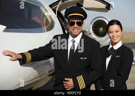 Porträt des mittleren Erwachsenenalter Airline-Piloten und Flugbegleiter vor Flugzeug. Stockfoto