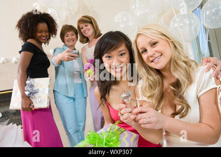Braut sitzt mit ihrem Freund zeigen großes Engagement Ring an Bridal Shower Stockfoto