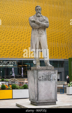 Statue von Friedrich Engels vor einem gelben Fassade in Tony Wilson neben Home Mcr-Kino in Manchester, Großbritannien Stockfoto