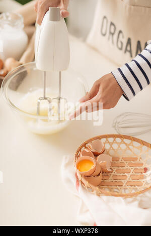 Männliche Hände schlagen Eiweiß Creme mit Mixer in der Schüssel Stockfoto