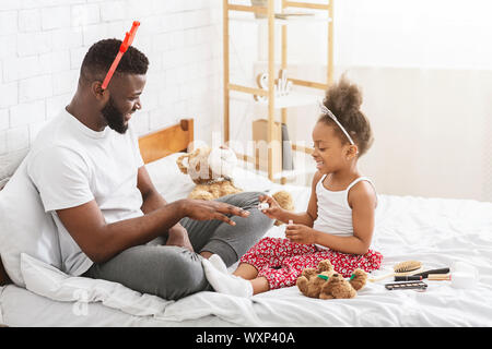 African American Girl Malerei ihr Vati Nägel, sitzen auf dem Bett Stockfoto