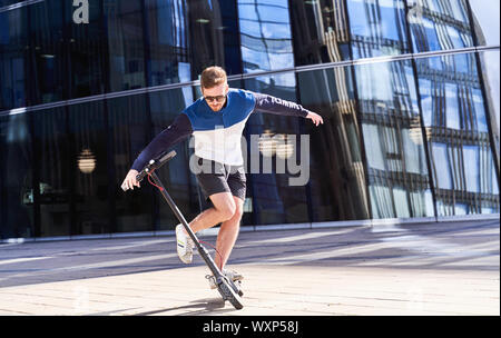 Junger Mann Ausbildung bei scooter in der modernen Stadt. Stockfoto