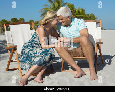 Volle Länge des romantischen senior Paar auf Liegestühle am Strand Stockfoto