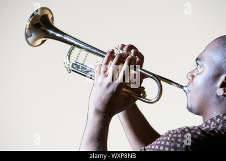 Seitenansicht einer afrikanischen amerikanischen Mann spielt Trompete gegen grauer Hintergrund Stockfoto