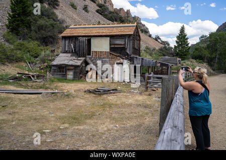 Frau touristische nimmt Fotos mit einem Telefon der verlassenen Gebäude in der bayhorse Geisterstadt in Idaho Stockfoto