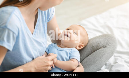 Adorable kleine Kind Lächeln während auf Mutters Schoß liegend Stockfoto