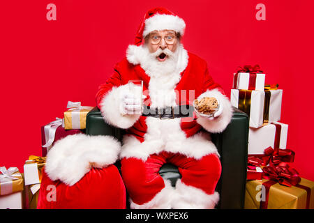 Spaß Freude Winter wünschen Dezember noel Reife im Alter von Nikolaus in headwear weißen Bart auf Rot/ Hintergrund geöffneten Mund isoliert starrenden Augen unglaublich Stockfoto