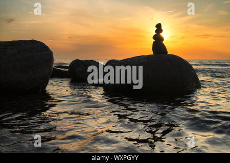 Meer mit großen Steinen bei Sonnenuntergang Stockfoto