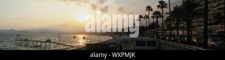 Panoramablick auf den Strand von Cannes, berühmte Stadt an der Französischen Riviera bei Sonnenuntergang mit Menschen Schwimmen im Sommer - Mittelmeer, Frankreich, Eur Stockfoto