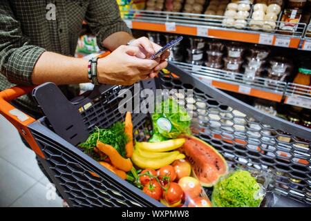 Mann mit Smartphone Einkaufen im Supermarkt Stockfoto