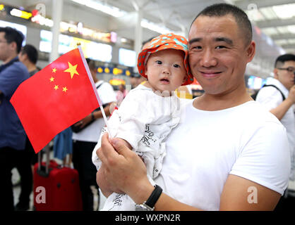 (190917) - SHANGHAI, Sept. 17, 2019 (Xinhua) - ein Mann nimmt Teil an einem Flash Mob mit einem Kind in Shanghai Hongqiao Bahnhof im Osten China Shanghai, Sept. 17, 2019. Teilnehmer im Chor patriotische Lieder während der Flash Mob als Weise des 70. Jahrestages der Gründung der Volksrepublik China zu feiern. (Xinhua / Chen Fei) Stockfoto