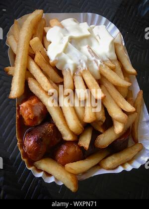 Currywurst & Pommes: Berühmte deutsche Fast Food (Currywurst mit Pommes Frites und Curry Sauce) mit Ketchup und Mayonaise Stockfoto