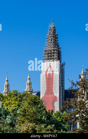Rathaus (Rathaus) Turm von Gerüsten (2019) und schützende Folie mit Yoga Illustration - Wien, Österreich. Stockfoto