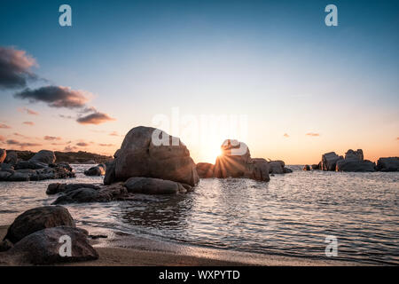 Dramatischer Sonnenaufgang über dem Mittelmeer und große Granitblöcke, die an der Küste von Cavallo Insel im Archipel Lavezzi von Korsika Stockfoto