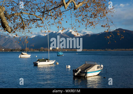 Alpinen See mit Booten und schneebedeckten Berg in Locarno, Schweiz. Stockfoto