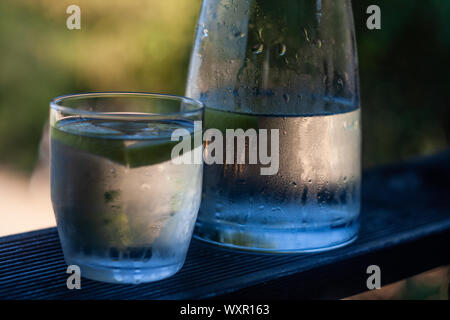 Flasche und Glas kaltes Wasser mit Wassertropfen Stockfoto