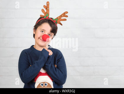 Frohe Weihnachten. Kind in einem Rudolph Rentier Weihnachten Kostüm auf Stein Hintergrund Stockfoto