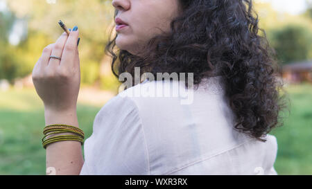 Der Jugendliche rauchen Marihuana gemeinsame im Freien. Die junge Frau Rauch cannabis Blunt, close-up. Cannabis ist ein Konzept der pflanzliche Alternative Stockfoto