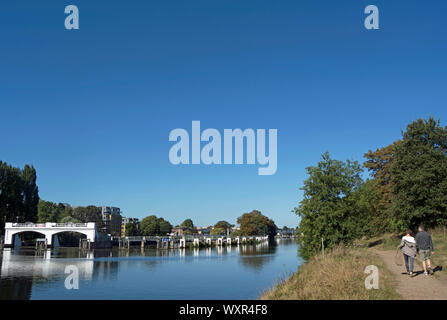 Ein Mann und eine Frau gehen auf den Schinken, Surrey, England, Seite der Themse in der Nähe von Teddington Wehr Stockfoto