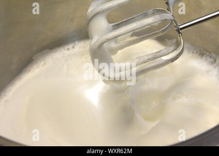 Geschlagener Eischnee und Zucker, Edelstahl Topf zum Backen cream Topping - eine moderne Küche Mixer verwendet das Eiweiß zu schlagen. Stockfoto