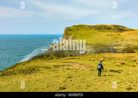 Ein Wanderer nähert sich die Landspitze von rubha Cruinn mit Spray aus dem Allt Mheididh Wasserfall, Talisker Bay, Minginish, Isle of Skye, Schottland, Großbritannien Stockfoto