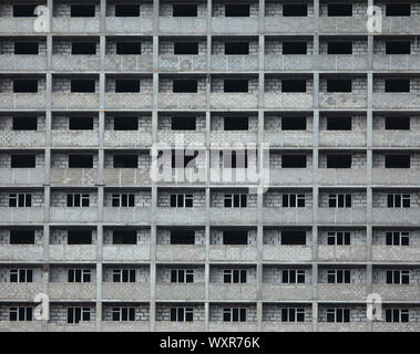 Das Fragment der Fassade des Unfertigen und Verlassenen monolithischen Wohngebäude. Hintergrund mit Windows dem mehrstöckigen Gebäude Stockfoto