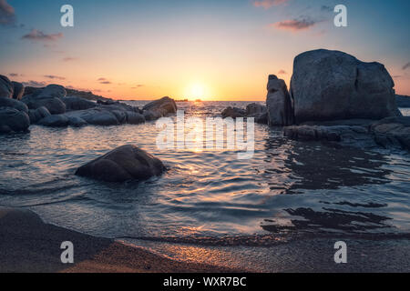 Dramatischer Sonnenaufgang über dem Mittelmeer und große Granitblöcke, die an der Küste von Cavallo Insel im Archipel Lavezzi von Korsika Stockfoto