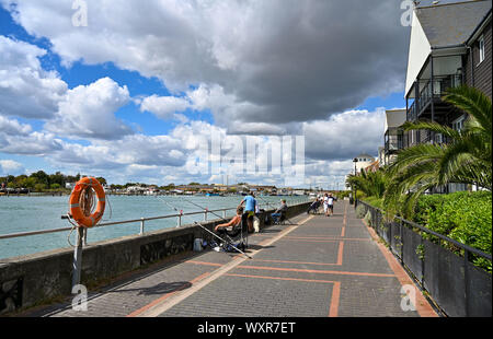 Fischer auf dem Fluss Arun in Littlehampton West Sussex Großbritannien mit Blick auf Häuser und Wohnungen Stockfoto