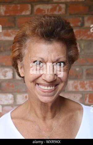 Porträt einer älteren Frau mit braunen Augen und Zähne baring Lächeln Stockfoto