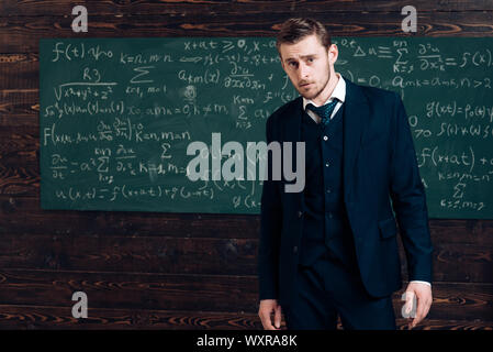 Porträt der jungen intelligenter Schüler in Elite College. Aristokrat mit perfekter Frisur und kurze Borsten stehend vor der grünen Platine isoliert. Stockfoto