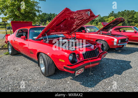 Eine lokale Auto Club Show in einen Parkplatz mit zwei lebhaften rot vintage camaros mit Öffnen der Hauben der Muskelkraft zwischen den beiden Autos zu zeigen closeu Stockfoto