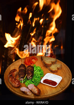 Teller appetitlich mit Salat und Brot gehalten. Fleisch rollt auf Holzspieße, Shish Kebab, gegrillte Würstchen mit Tomaten und saure Sahne Sauce o serviert. Stockfoto