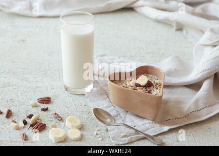 Schüssel mit hausgemachtem Müsli mit Nüssen, Beeren, getrocknete Früchte, Glas Milch und Honig. gesundes Frühstück. Stockfoto