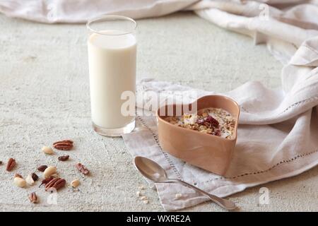 Schüssel mit hausgemachtem Müsli mit Nüssen, Beeren, getrocknete Früchte, Glas Milch und Honig. gesundes Frühstück. Stockfoto