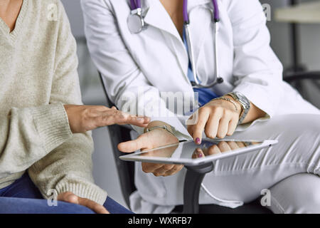 Ärztin im Gespräch mit einem Patienten auf eine Tablette. Stockfoto
