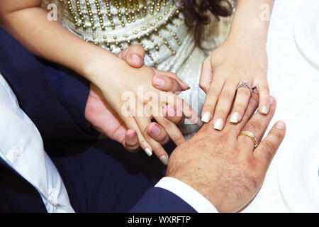 Mittelteil der Paare halten sich an den Händen, während comferting einander. Der Mann nahm die Hand der Braut. Die Paare, die Braut und der Bräutigam halten sich an den Händen. Stockfoto