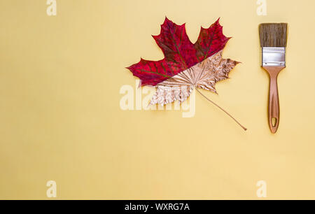 Pinsel und Maple Leaf auf gelbem Hintergrund. Herbst Konzept, flach. Kopieren Sie Platz. Stockfoto