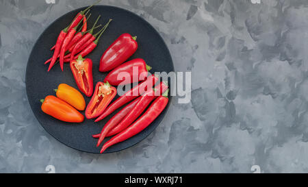 Bunte Mischung der frischesten und heißesten chili peppers und Bulgarischen farbigen Pfeffer auf einer schwarzen Platte. Stockfoto