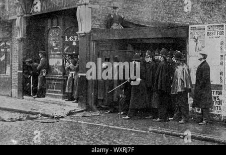 Winston Churchill bei der Belagerung der Sidney Street, 3. Januar 1911. Winston Churchill, der damalige Innenminister bei der Belagerung der Sidney Street. Churchill ist ein Bild des Sidney Arms Public House, 131 Sidney Street. Die Belagerung der Sidney Street, auch bekannt als die Schlacht von Stepney, war ein Schusskampf im östlichen Teil Londons zwischen einer kombinierten Polizei- und Armeeeinheit und zwei lettischen Revolutionären. Stockfoto