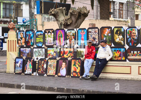 BANOS, ECUADOR - 22. FEBRUAR 2014: Nicht identifizierte Personen verkaufen Gemälde außerhalb des Parks Palomino Flores in der Ambato Straße in Baños, Ecuador Stockfoto