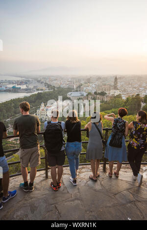 Touristen am Aussichtspunkt Gibralfaro mit Blick auf den Hafen von Malaga en Stadt, bei Sonnenuntergang, Andalusien, Spanien. Stockfoto