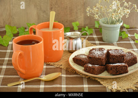 Kaffee und hausgemachten Brownies in einem rustikalen Fallen. Horizontales Format mit Schwerpunkt auf der Vorderseite des Brownies. Stockfoto