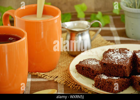 Kaffee und hausgemachten Brownies in einem rustikalen Fallen. Horizontales Format mit Schwerpunkt auf der Vorderseite des Brownies. Stockfoto